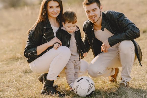 A family enjoys a warm day bonding and playing soccer outdoors in the park.