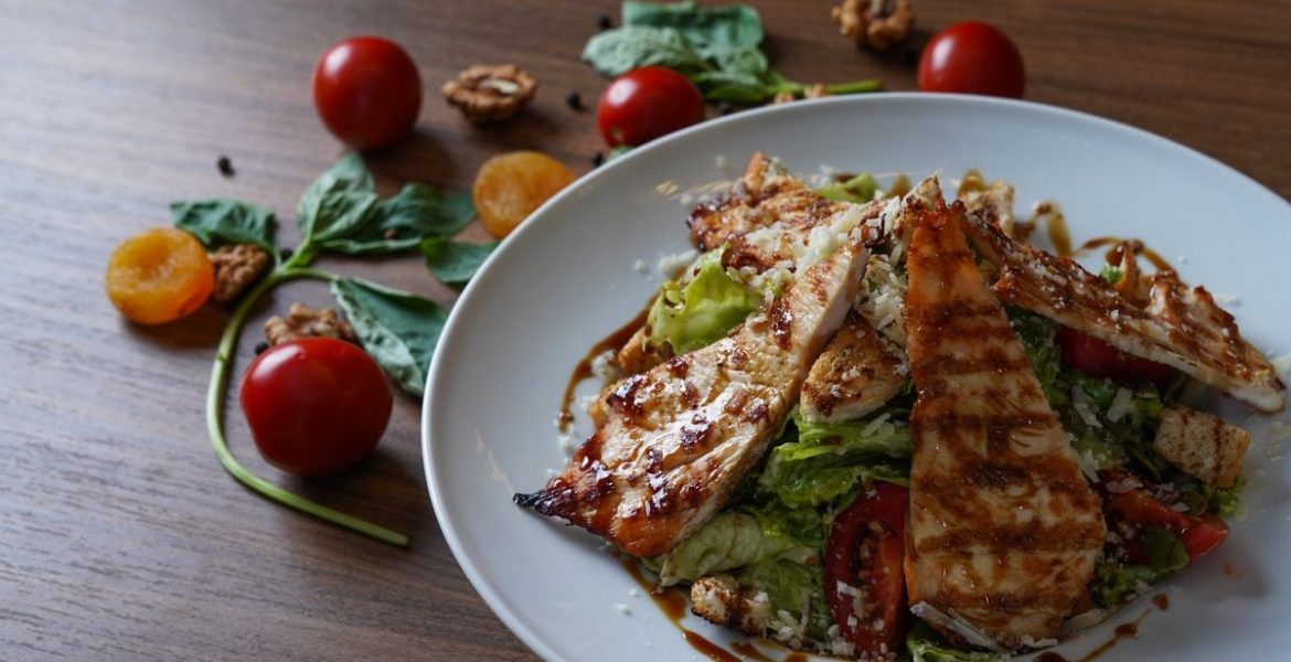 Delicious grilled chicken salad served with fresh tomatoes and walnuts on the side.