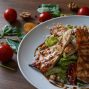 Delicious grilled chicken salad served with fresh tomatoes and walnuts on the side.